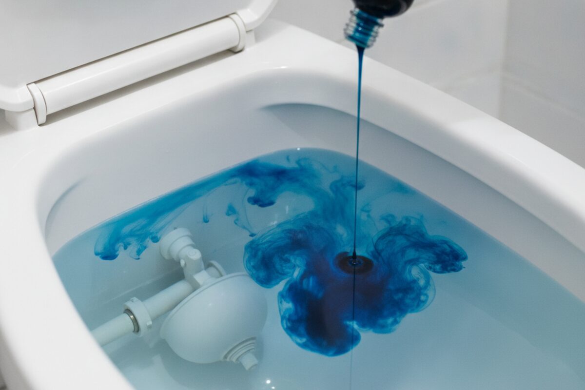 Blue food coloring being added to a toilet tank for a leak test