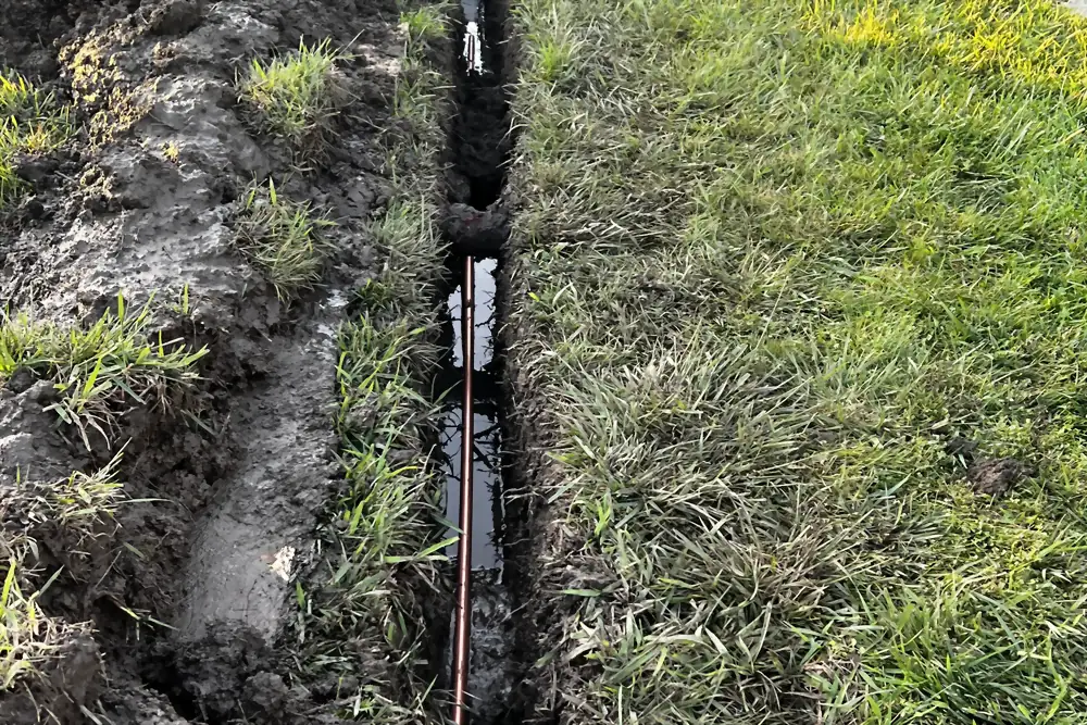 New copper main water line run through an open trench before backfill.