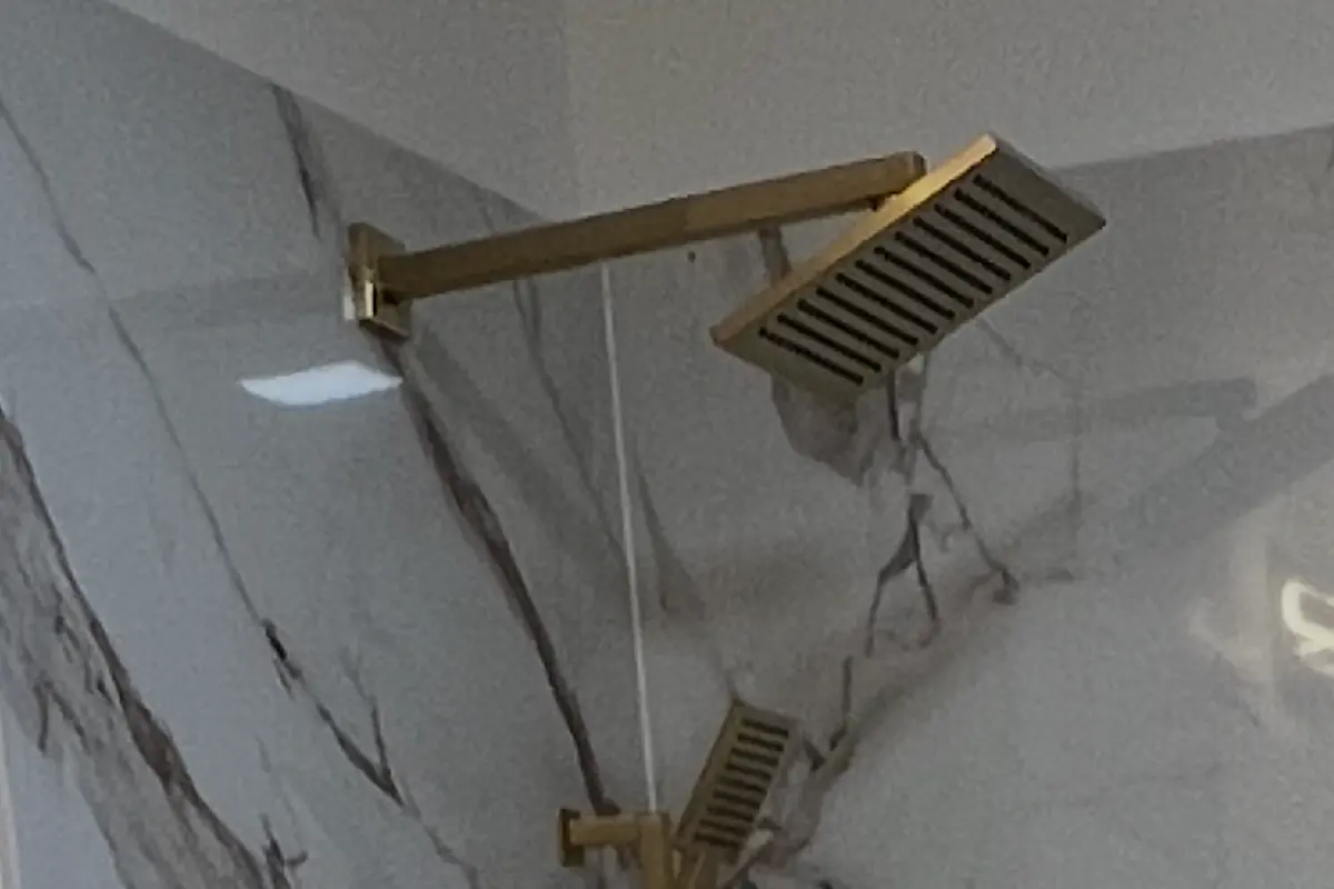 New brushed gold shower valve and rain head fixtures installed.
